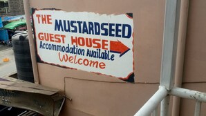Opastekyltti, jossa kerrotaan, että The Mustardseed -vierastalossa on majoitustiloja asiakkaille.