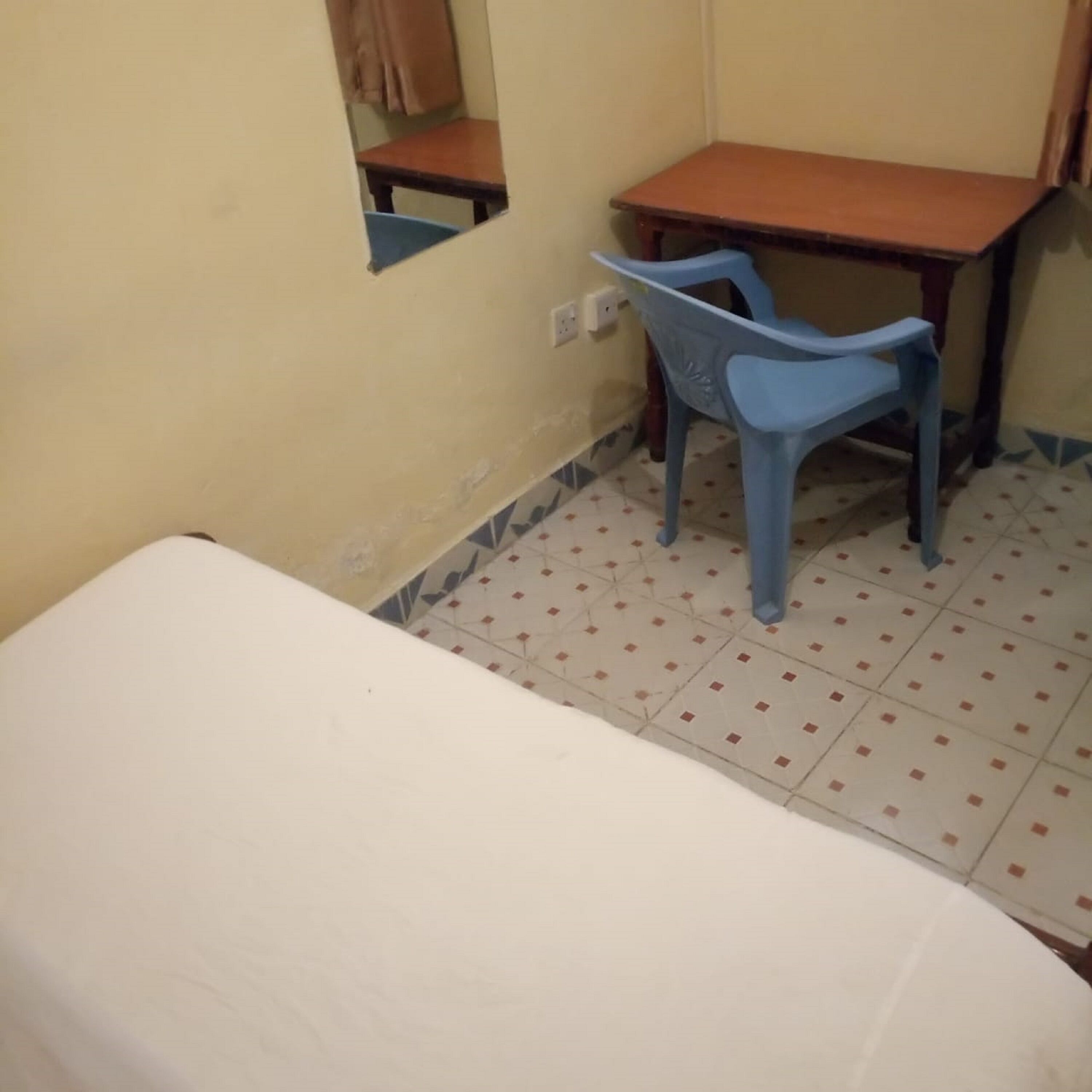 A small room with a single bed, a desk, and a chair.