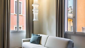 Una sala de estar moderna con un sofá blanco, un otoman redondo y una lámpara colgante blanca de diseño único.