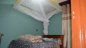 Un dormitorio con cama, mosquitero y cortinas.