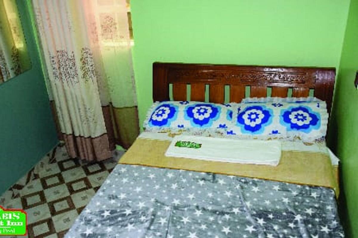 A room with a bed, a window with curtains, and a patterned floor.