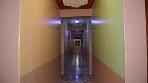 Un pasillo con piso estampado, techo decorativo y una puerta al final.