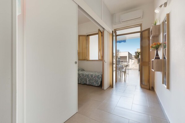 A hallway with a bed, a dining area, and a view of the outside.