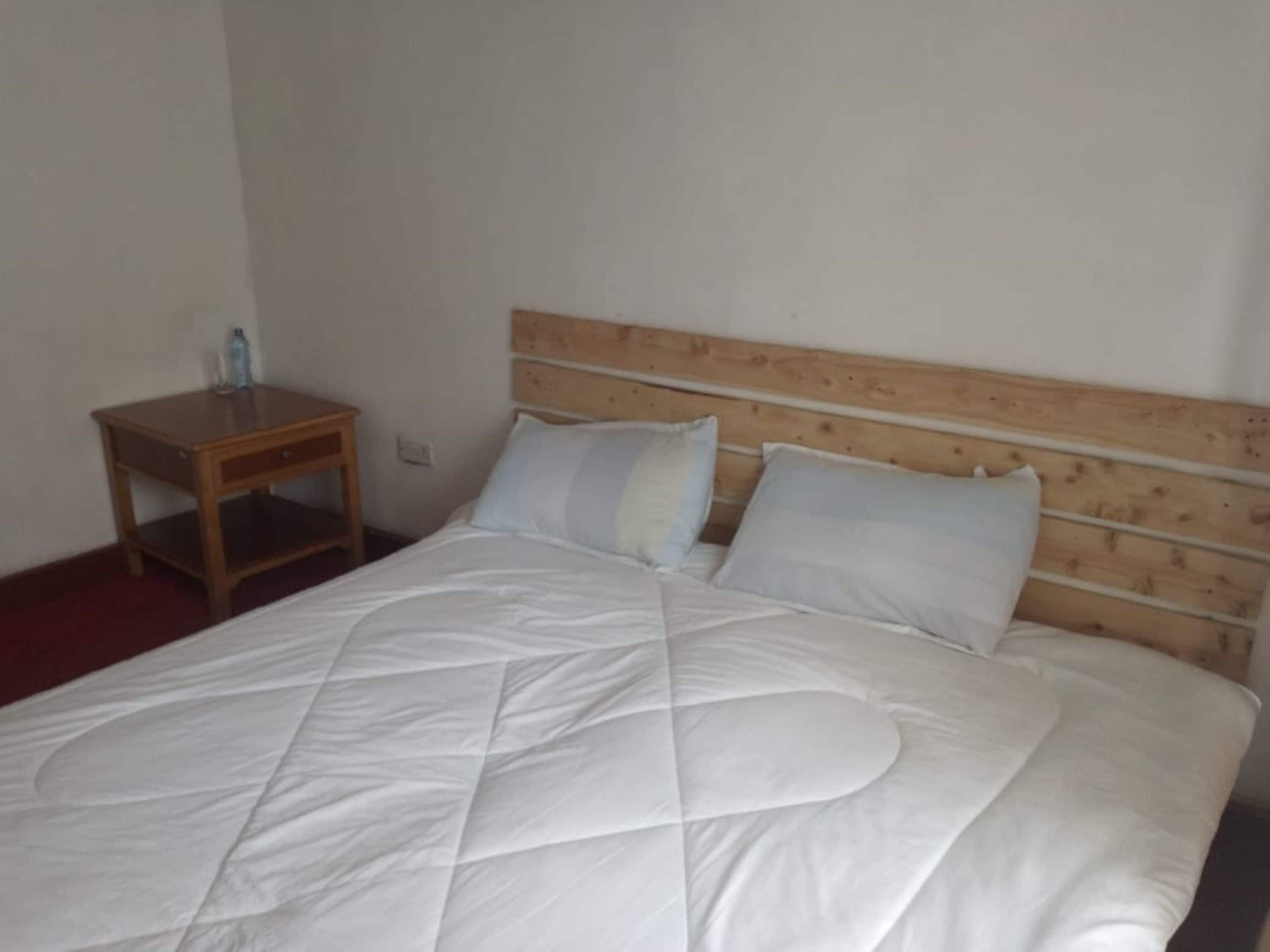 Un lit avec une tête de lit en bois et du linge de lit blanc.