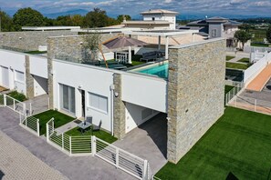 A modern house with a rooftop pool, stone walls, and a well-maintained lawn.