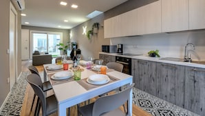 A modern kitchen with grey cabinets, a white countertop, and a dining area with a table set for four.