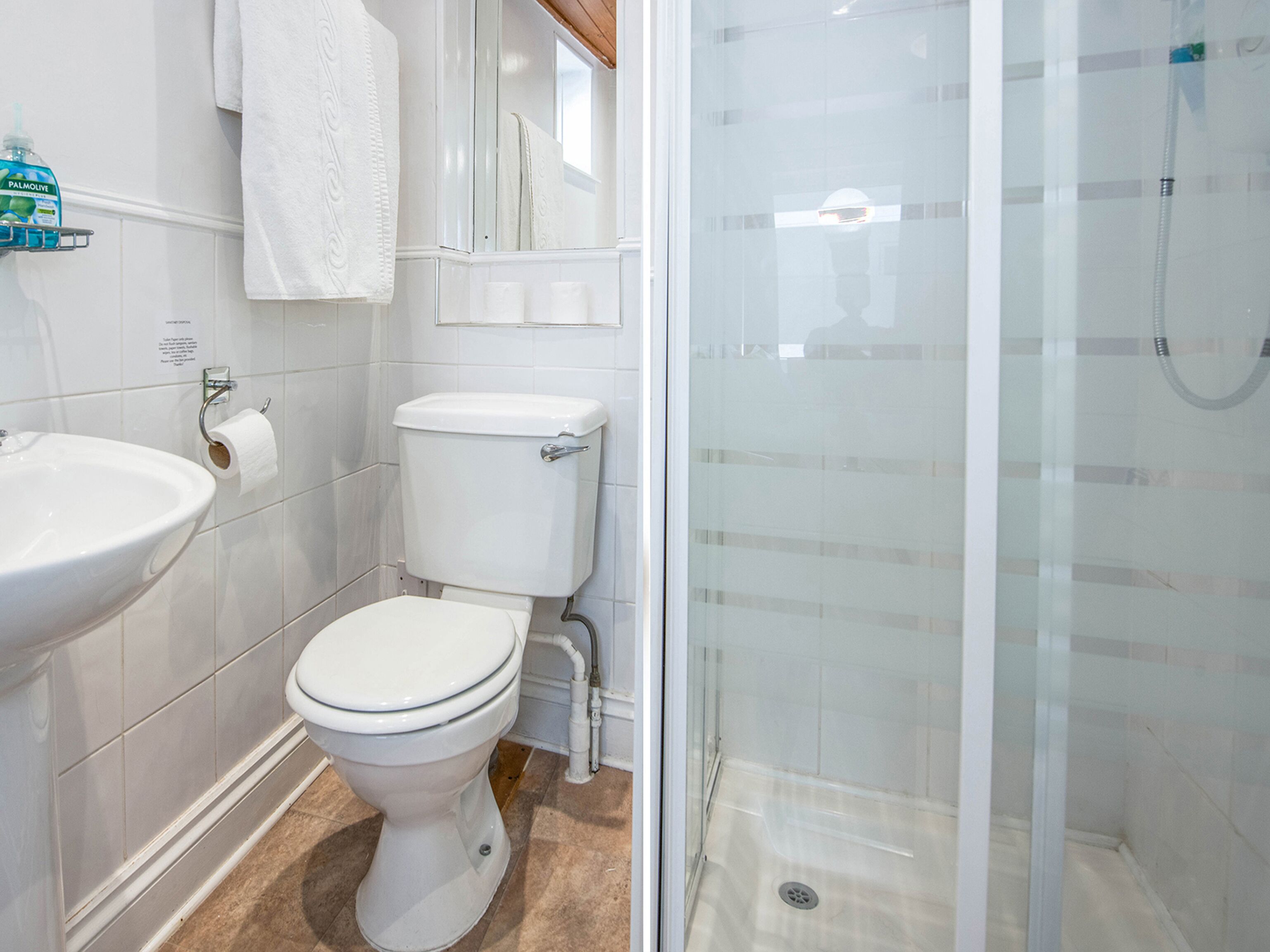 A bathroom with a toilet, sink, and glass shower enclosure.