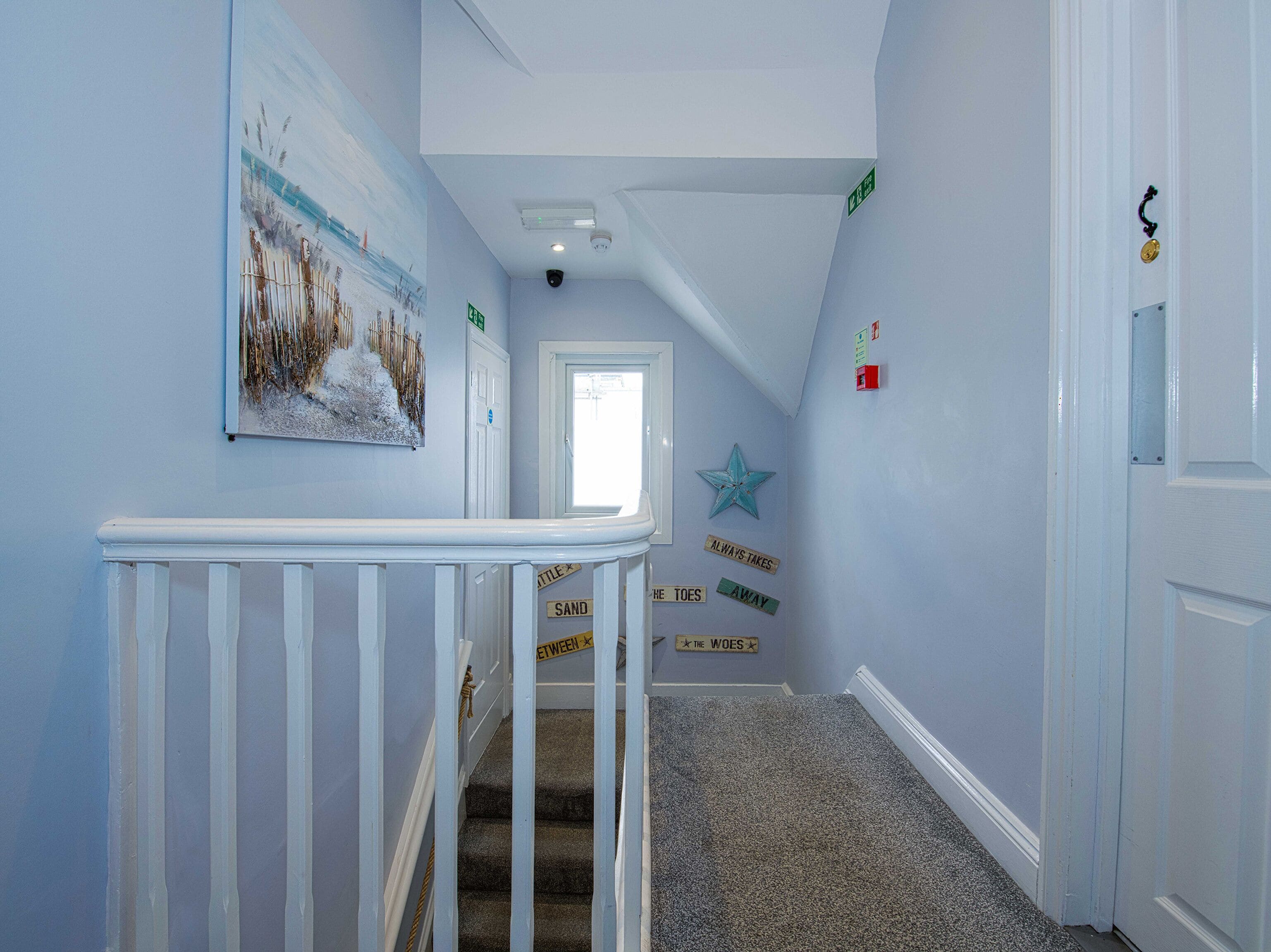 A hallway with a white railing, a star decoration, and motivational signs on the wall.