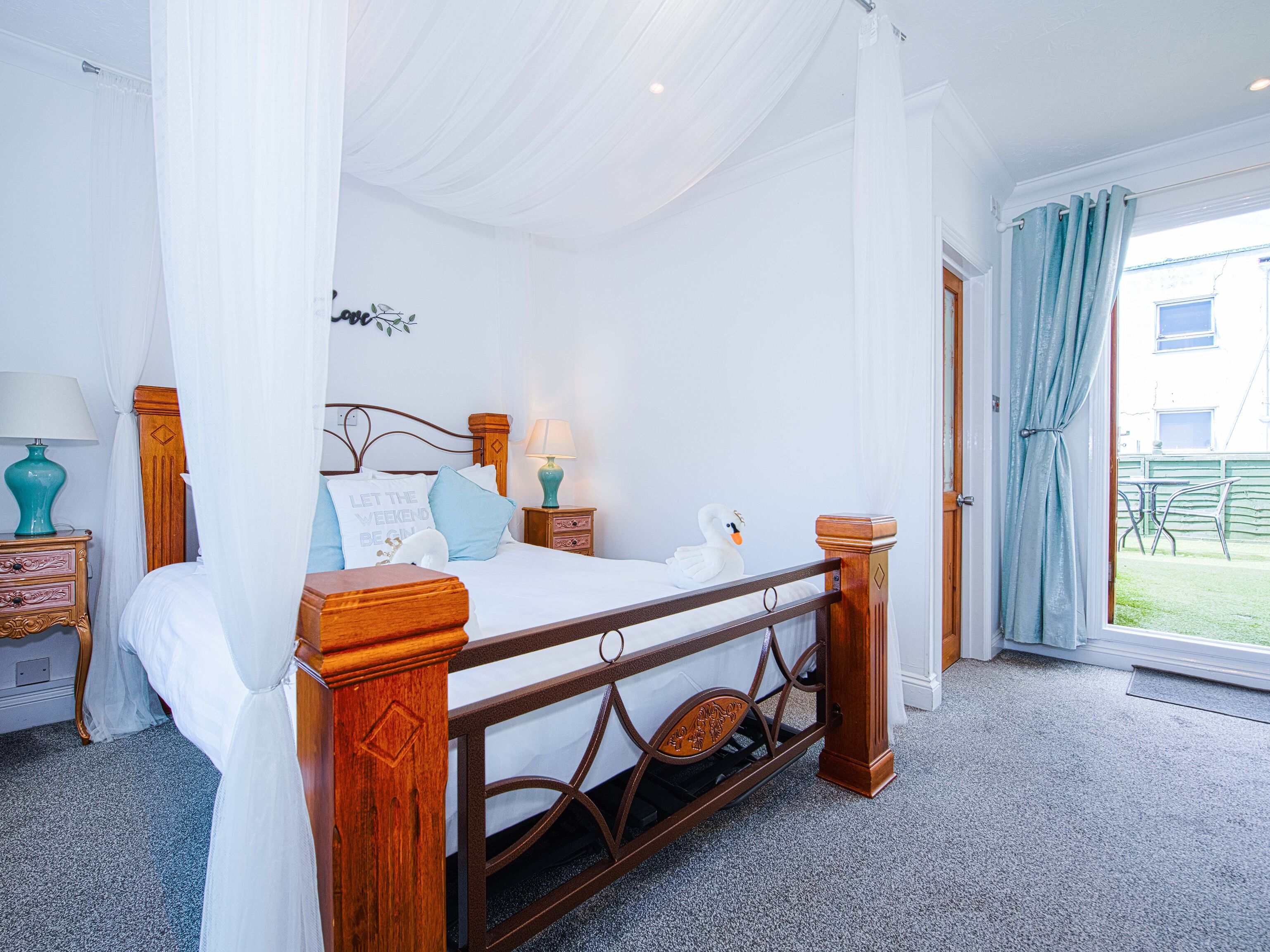 Une chambre à coucher avec un lit à baldaquin, une table de chevet avec une lampe et une décoration en forme de cygne.