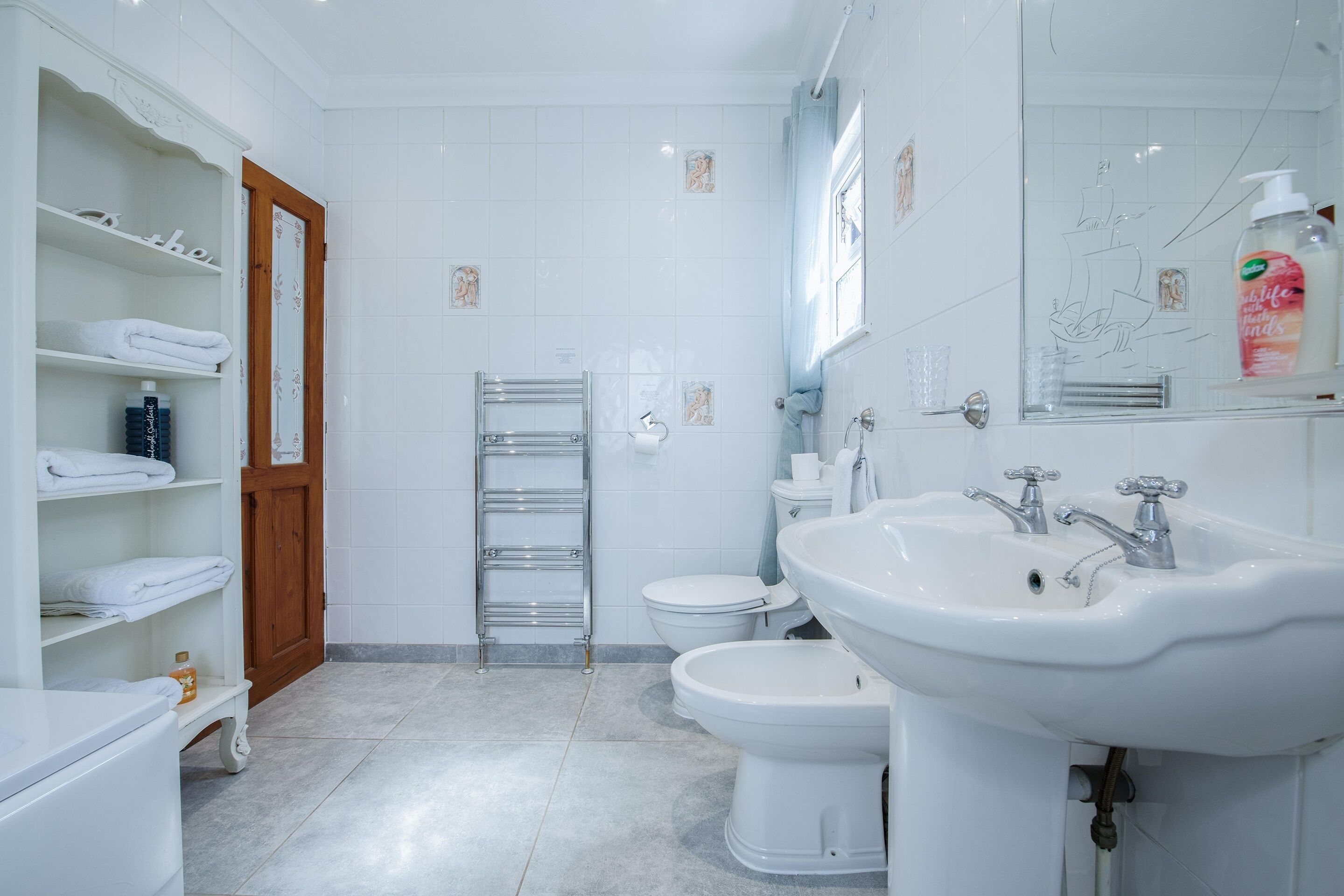 Une salle de bain moderne avec des éléments d’équipement blancs, un porte-serviettes, des toilettes et un lavabo.