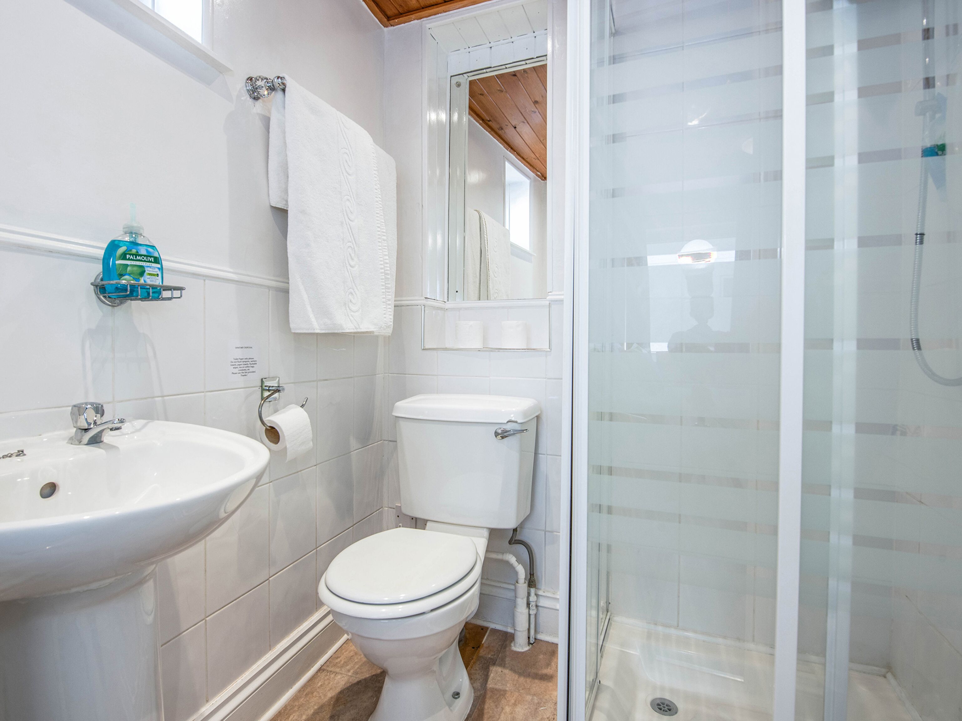 A bathroom with a white sink, toilet, and glass shower enclosure.