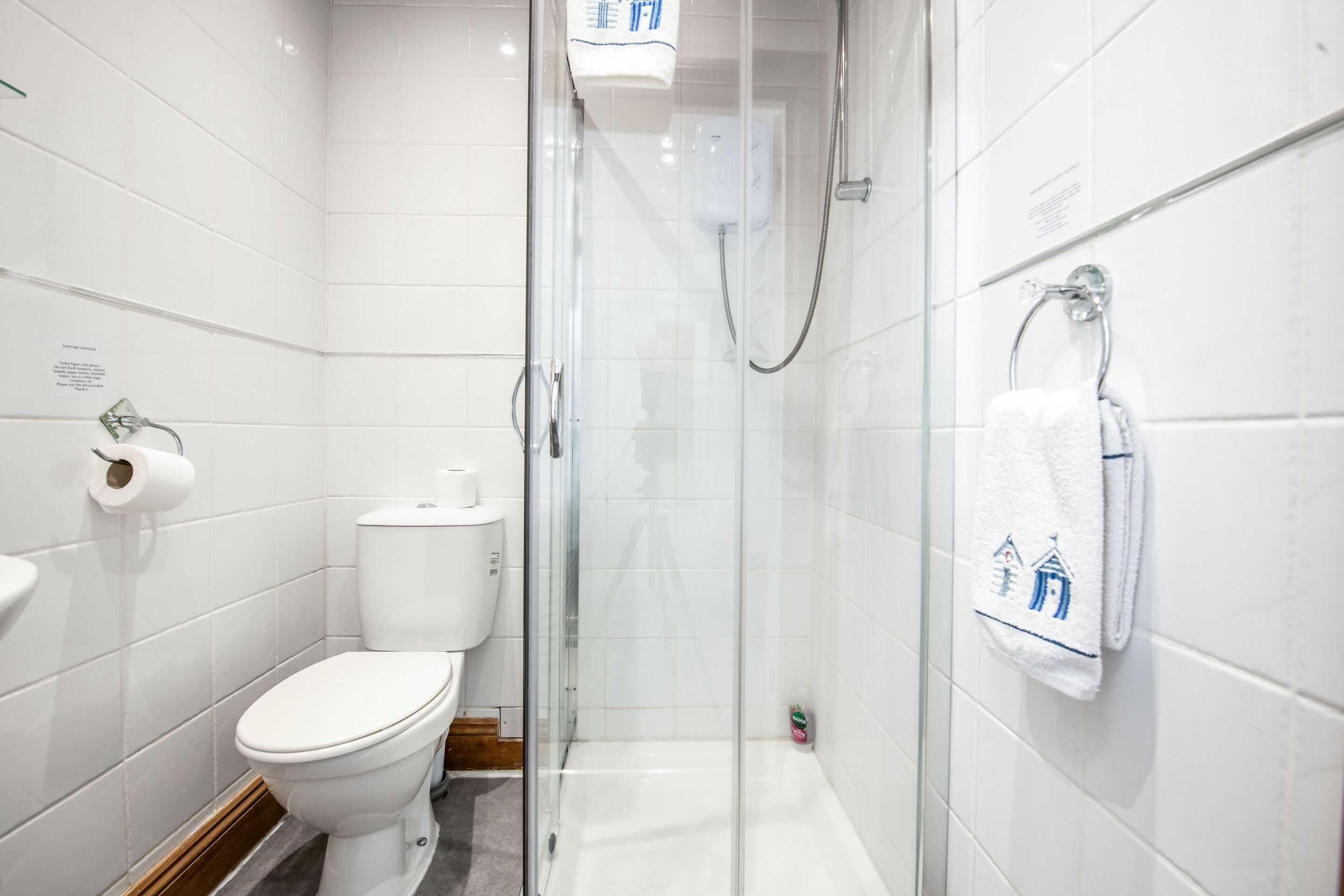 A bathroom with a toilet, a glass-enclosed shower, and a towel rack.