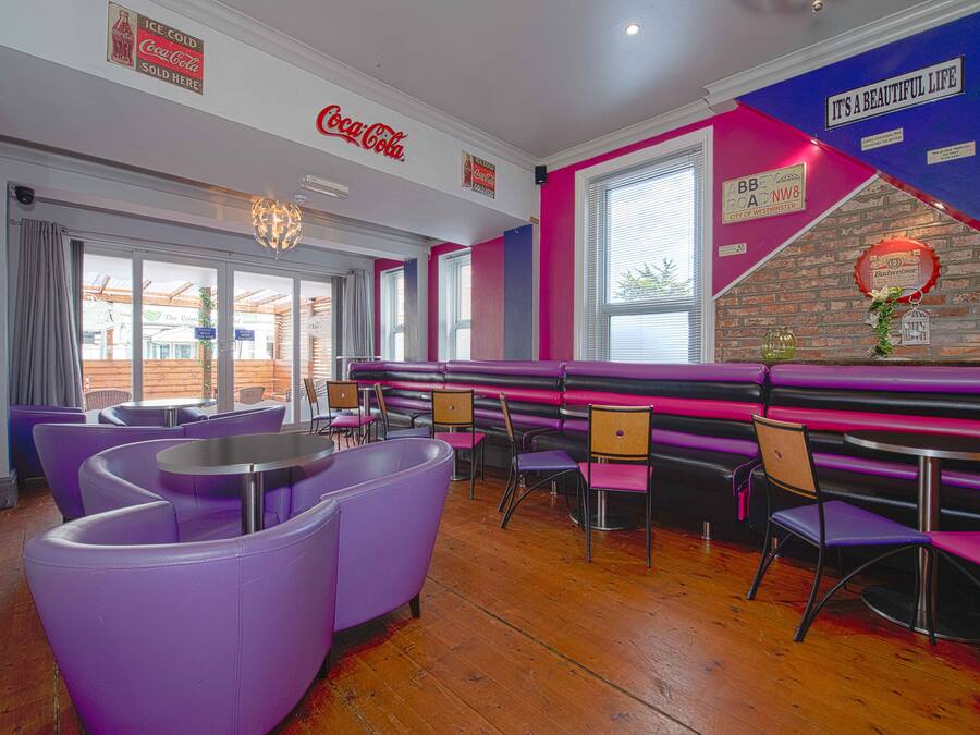 A restaurant interior with purple seating, a Coca-Cola sign, and a 'It's a Beautiful Life' sign on the wall.