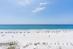 Une plage de sable blanc, avec une eau d’un bleu limpide et des parasols.