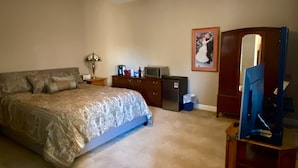 Une chambre à coucher comprenant un lit, un bureau, une chaise, un téléviseur et un ventilateur de plafond.