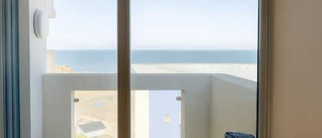 Una habitación con un ventanal grande con vista a una playa y el océano.