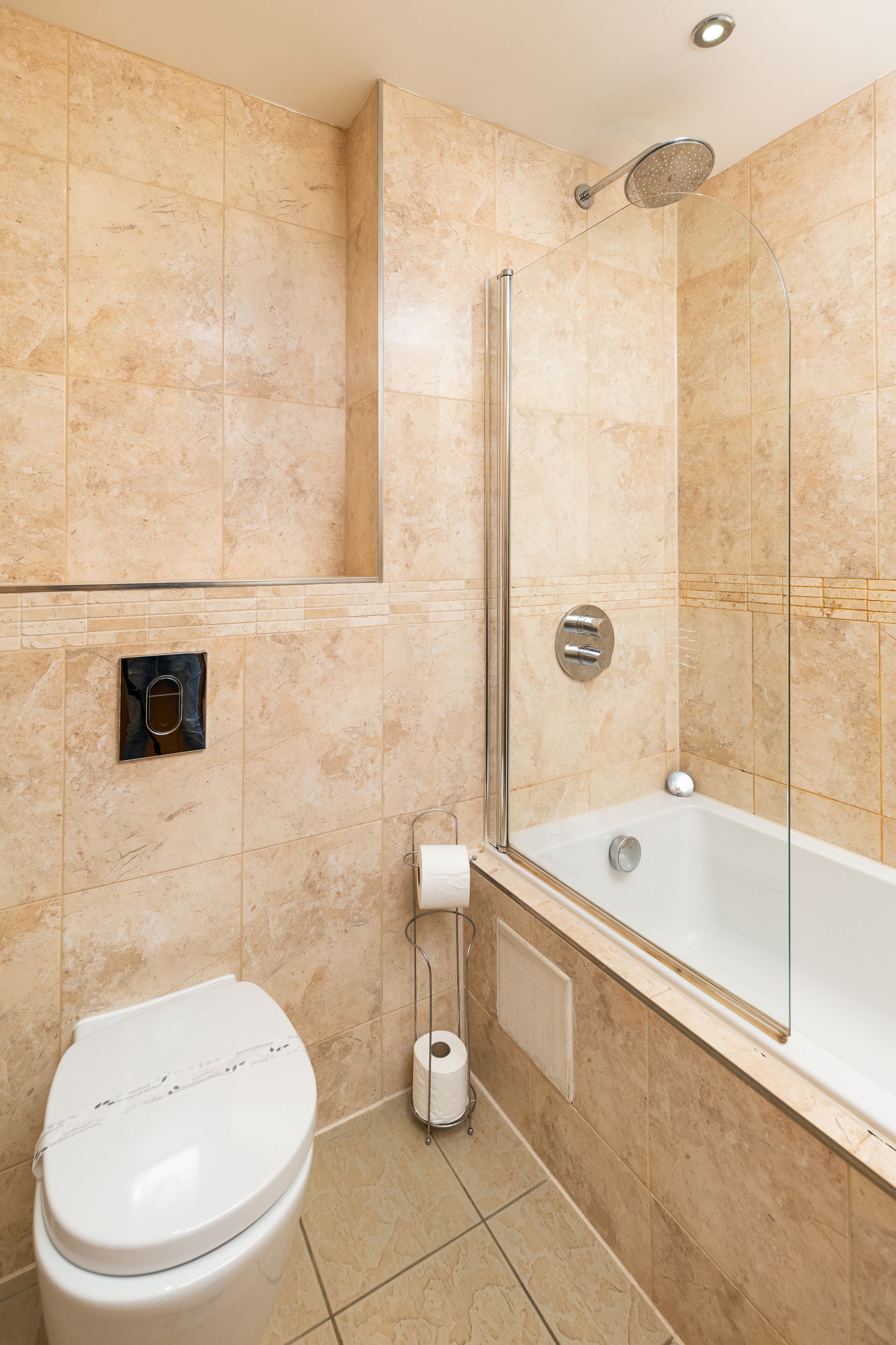 A modern bathroom with a toilet, a shower with a glass enclosure, and a bathtub.