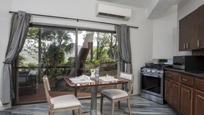 Une cuisine moderne dotée d’une grande fenêtre, d’une table à manger avec des chaises, et d’un mur en pierre visible à travers la fenêtre.