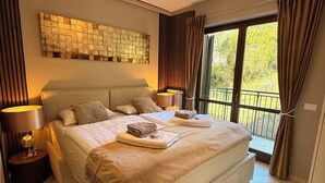 Une chambre spacieuse avec un grand lit, une œuvre d’art accrochée au mur et une vue sur le balcon.