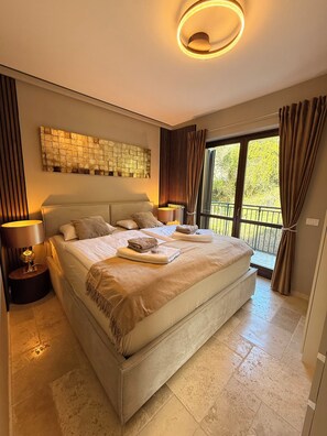 Un dormitorio amplio con una cama grande, una obra de arte en la pared y vistas al balcón.