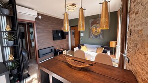 Une chambre d’hôtel moderne avec une table à manger en bois, un hamac, une télévision et un tableau représentant un Bouddha.