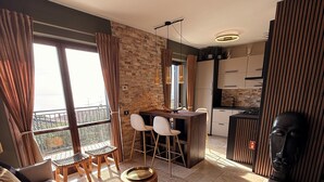 Un appartement moderne comprenant un coin repas, une cuisine et une grande fenêtre avec des rideaux.