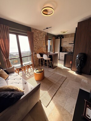Un apartamento moderno con comedor, cocina y un amplio ventanal con cortinas.