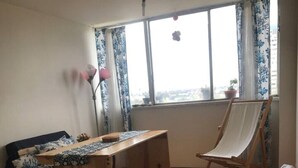 Une pièce comprenant un lit, un bureau, une chaise et une fenêtre avec des rideaux.