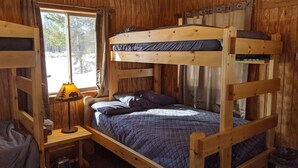A wooden bunk bed room with a window, a bedside table with a lamp, and a view of trees outside. - Rustic Retreat Cabin for Families/Sm Groups, "Shalom" (South Range)