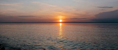Un atardecer sobre un cuerpo de agua tranquilo, con un horizonte lejano.
