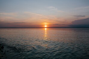 A sunset over a calm body of water with a distant horizon.