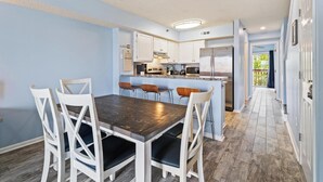 Una cocina moderna con armarios blancos, un comedor de madera oscura y vistas al exterior.