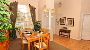 A dining room with a wooden table set for four, surrounded by chairs. There is a bench against the wall and a potted plant to the left. - 213 BS (Davenport)