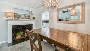 Un comedor con mesa y sillas de madera, chimenea y candelabro.