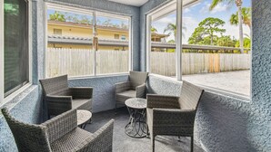 Un solárium con muebles de mimbre, ventanas amplias y vista a una zona residencial.