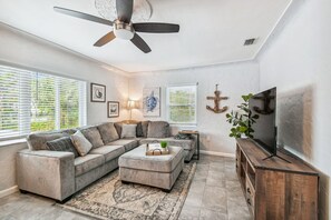 Relax in this stylish living room with a large L-shaped sofa, flat-screen TV, and decorative plant.