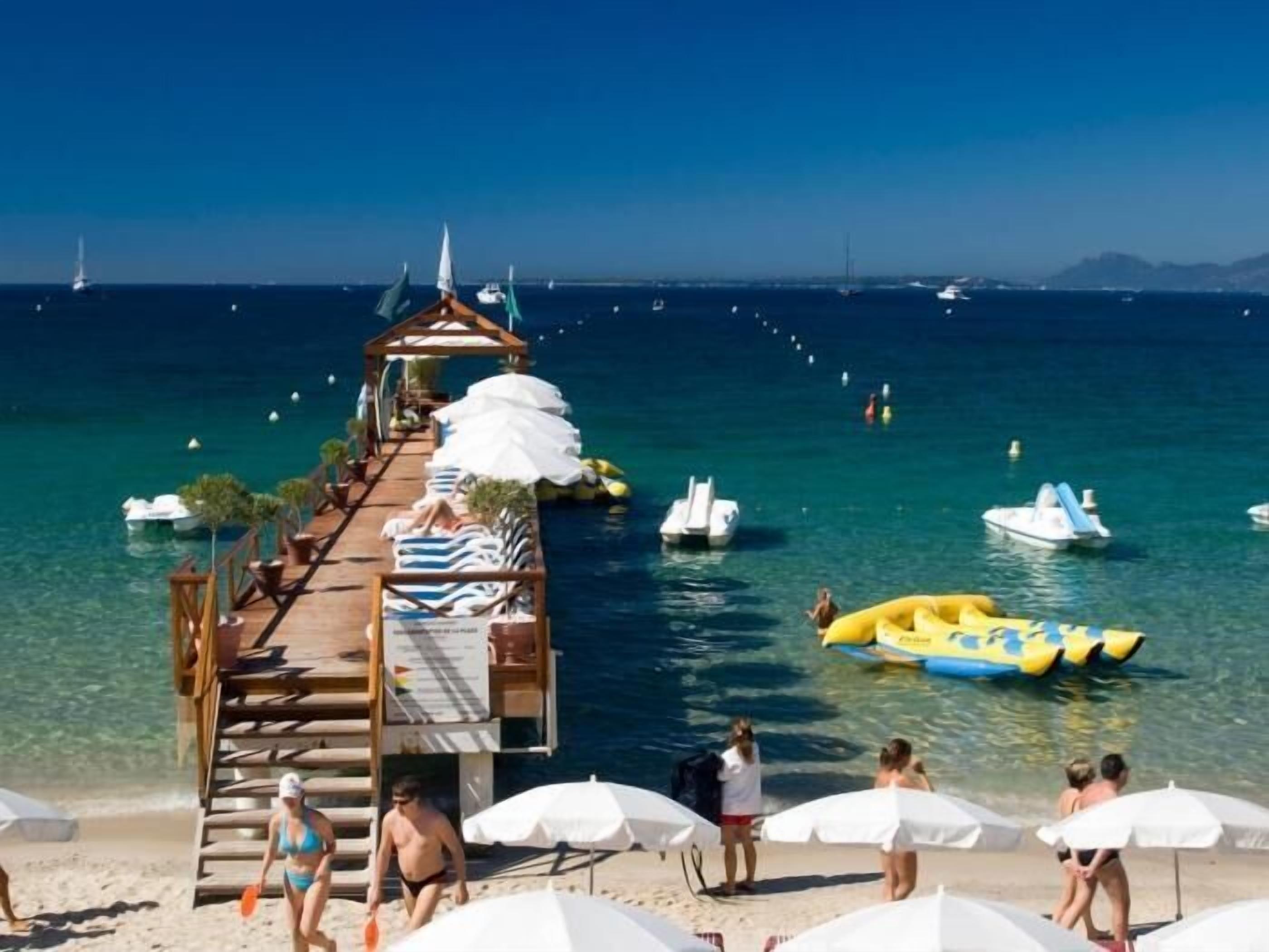 A pier extending into the sea with boats and a yellow inflatable raft.