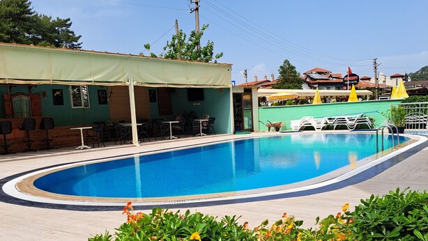 A swimming pool with a sunshade, surrounded by green plants and flowers. - Miramonte Apart Hotel (Marmaris)