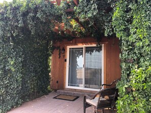 Een houten gebouw met een schuifdeur, omgeven door weelderige begroeiing.