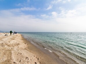 Une plage où l’on peut voir des gens pêcher, avec une eau claire et une mer calme.