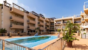 Um edifício residencial com vários andares, piscina, varandas e plantas em vasos.