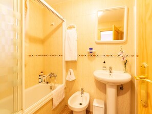 Une salle de bain équipée d’une baignoire, d’un lavabo, d’un bidet et d’un miroir.