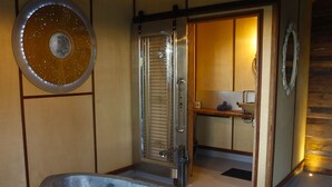 Une baignoire en pierre dans une pièce aux murs lambrés et dotée d’un luminaire suspendu.