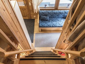 A wooden staircase leading to a room with a blue sofa and patterned cushions.