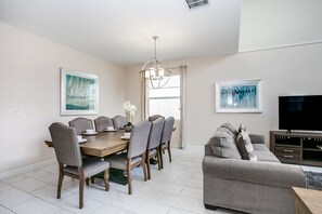 A dining area with a wooden table and chairs, a chandelier, and artwork on the walls. - 1585tempo (Davenport)