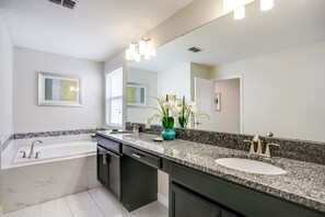 A modern bathroom with a large mirror, a bathtub, and a sink. - 1585tempo (Davenport)