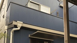 Un bâtiment moderne à la façade bleu foncé, avec une porte marron foncé et une petite fenêtre située au-dessus de la porte.