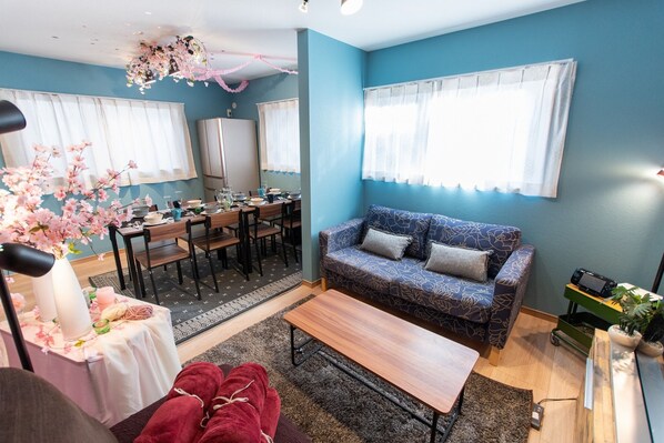 A living room with a blue sofa, a dining table set, and a kitchen area. - And Koenji (Tokyo)