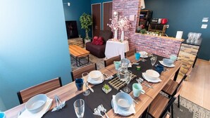 Un espace repas agrémenté d’un mur en briques apparentes, de tables et de chaises en bois.