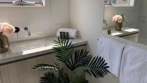 A modern bathroom with a sink, mirror, and a potted plant. - Delicate Bundoora townhouse 10 (Bundoora)